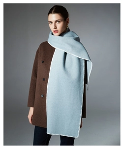Detail of light blue scarf with white hand-stitched edges over dark brown wool coat