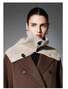 Detail of beige ribbed knit collar featuring black buttons and high neck texture