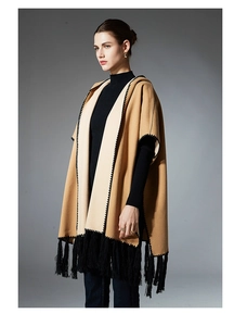 Detail of camel and beige hooded poncho with black fringe trim and zigzag stitching