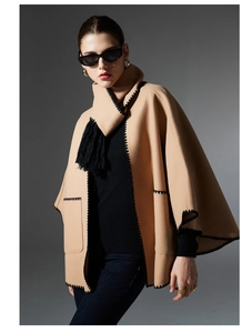 Detailed close-up of camel wool shawl featuring black scalloped edges and fringe trim
