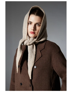 Detailed texture of beige knit wool triangle scarf worn with a brown pea coat