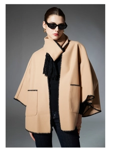 Detail of camel wool scarf jacket with black whipstitch edges and long tassels