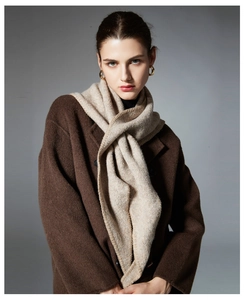 Detail of oat knitted triangle scarf with refined edging over a brown wool coat