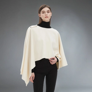 Elegant cream buttoned shawl cape for women styled with black turtleneck on grey background