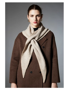 Detail of premium beige knit scarf paired with a brown wool coat and golden earrings