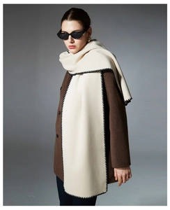 Detail of cream cashmere scarf with black wavy handmade stitched edges on wool coat