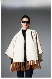 Detailed view of beige knit shawl featuring brown embroidery edges and long thick tassels
