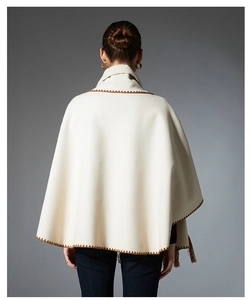Detail of cream cape shawl showing brown embroidery stitch and fringe tassels on the back