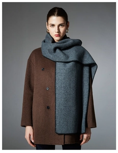 Detail of dark grey wool scarf featuring black whipstitch edges on a brown coat