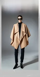 Detailed view of camel solid shawl with brown piping paired with boots and jeans