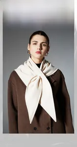 Detail of a creamy white thick triangle shawl paired with a brown wool coat in winter