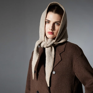 Chic beige knit triangle scarf for winter paired with a stylish wool coat on grey background
