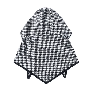 Détail d'une cape à capuche pied-de-poule noir et blanc avec ourlet pointu et pompons
