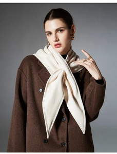 Close-up of soft cream knit scarf texture styled with a dark brown wool winter coat