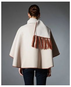 Close-up of beige knit shawl with brown embroidery stitch and long fringe detail