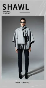Detailed view of grey knitted shawl featuring functional pockets and black fringe trim edges