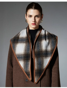 Detailed close-up of premium wool plaid scarf with refined brown stitched edge craftsmanship