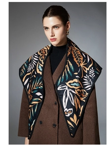 Close-up of winter triangle scarf with orange leaf patterns worn over a brown coat