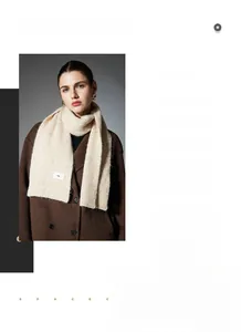 Close-up of cream knit scarf texture with a brand label on a wool scarf worn with a coat