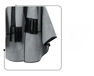 Detail of grey woolen shawl featuring black fringe trim and zigzag stitched edge