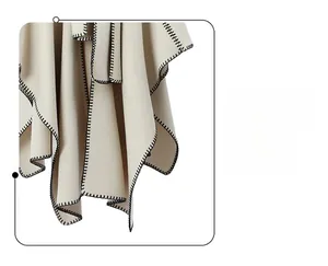 Detailed macro view of cream textile shawl with decorative black blanket stitch edging
