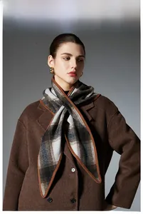 Detail of classic plaid wool scarf with brown and grey grid pattern and premium hemmed edge