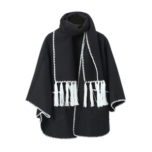 Close-up of black cape shawl with white contrast stitching and long fringed tassels