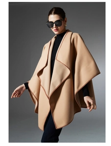 Close-up of camel wool poncho featuring premium brown leather piping and elegant draping