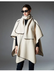 Detailed view of cream poncho with black whipstitch edges and matching scarf wrap