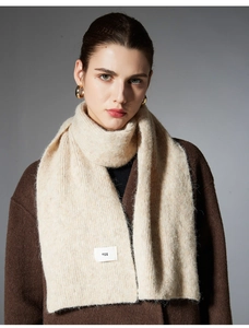 Detail of oat-beige knitted wool scarf featuring a woven label and soft ribbed texture