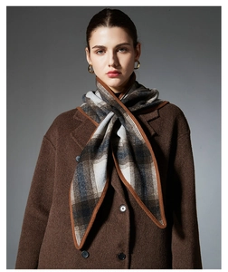 Detail of plaid wool scarf paired with dark brown coat showing rich fabric texture