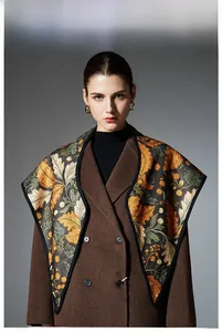 Detail of elegant leaf print shawl draped over a classic brown double-breasted wool coat
