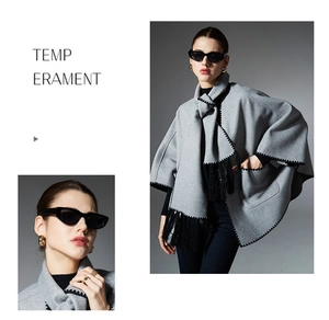 Detail of grey poncho shawl featuring black zigzag stitching and long tassel accents