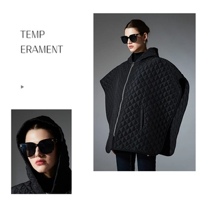 Detail of black quilted hooded poncho featuring metallic zipper and quilted diamond pattern