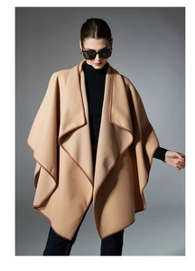 Detail shot of camel wool shawl cape showing dark brown contrast piping and premium texture