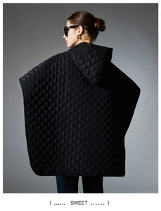 Detail of a women's black quilted hooded poncho featuring a classic diamond-stitch pattern