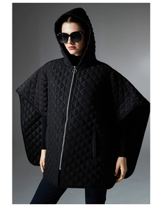 Detail of black quilted hooded poncho with diamond stitching and metal zip closure