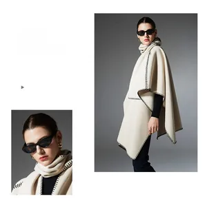 Detail view of beige knit shawl with decorative black whipstitch edges and premium texture