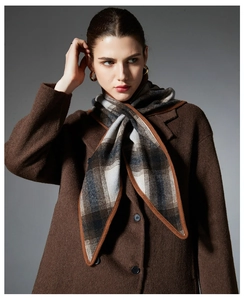 Detail of wool plaid scarf paired with a classic brown coat and gold hoop earrings
