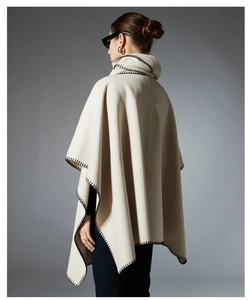 Detail view of beige wool poncho with elegant black whipstitch edges and high collar