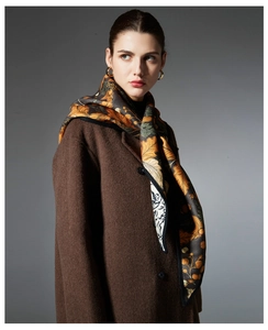 Detailed texture of women's autumn scarf with floral leaves and brown wool coat