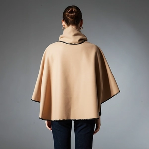Camel cape shawl with high collar and black scalloped trim shown from the back view