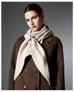 Detail of soft cream knitted triangle shawl draped over a brown wool coat with soft texture