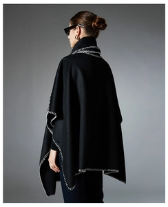 Detail view of black cape shawl featuring bold white contrast stitching on high-quality fabric