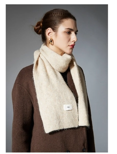 Close-up of premium oatmeal knit wool scarf showing soft texture and logo label detail