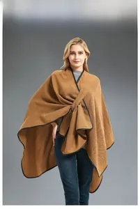 Detail of camel knit poncho with black trim and elegant twisted buckle closure