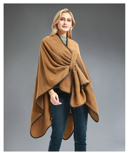 Detail of a brown knitted poncho featuring black leather trim and honeycomb texture fabric