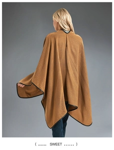 Detail view of camel knit poncho cape featuring contrast black piping and elegant drape