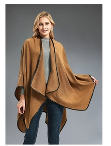 Detail of camel knit poncho showing black leather trim edges and soft textured fabric
