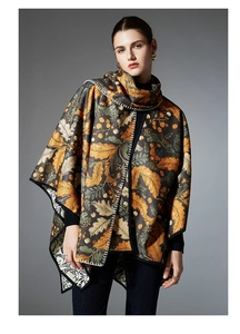 Close-up of autumnal leaf print shawl with white blanket-stitch edges and soft fabric